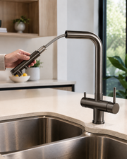Hand extending the pull-out spray head of the gunmetal mixer tap